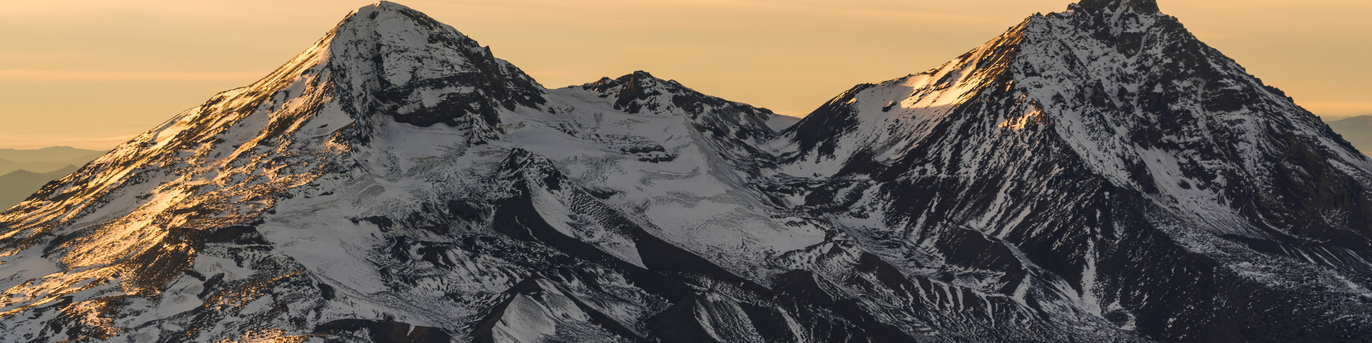 Snowy mountain peaks against an orange sky