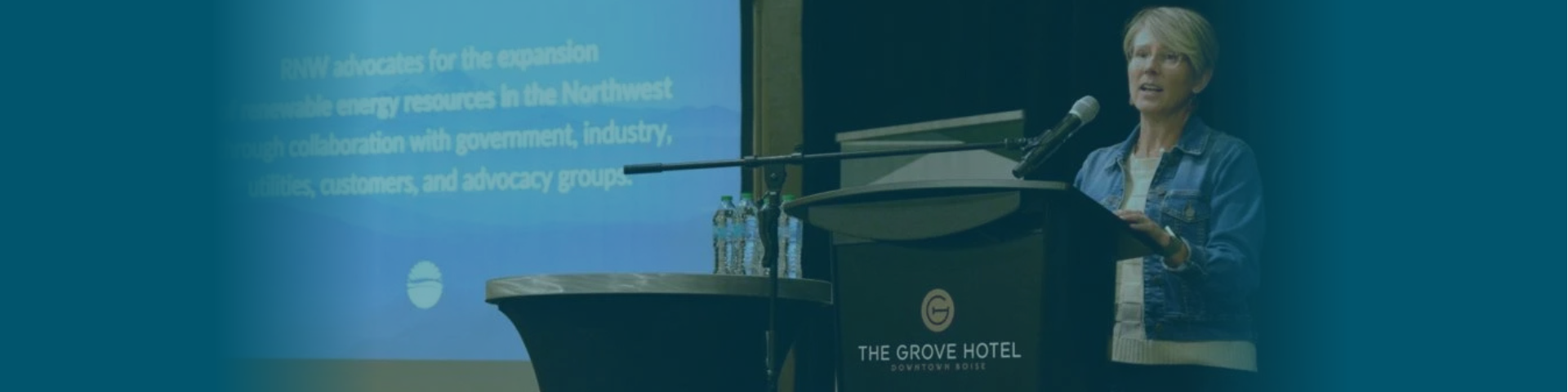 Nicole standing at a podium next to a projector screen with RNW's mission statement projected onto it